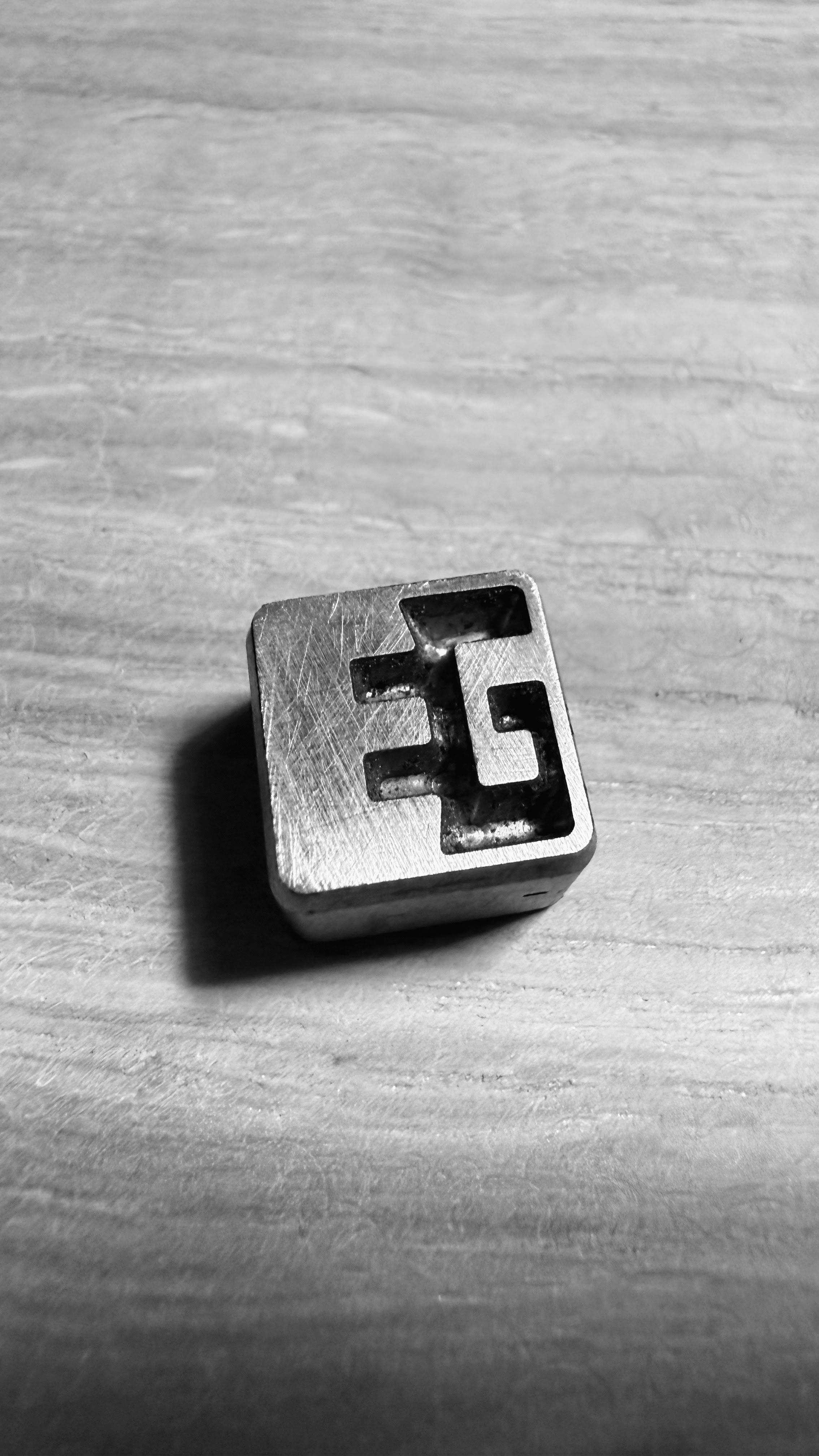 Metallic block with a geometric design on a wooden surface