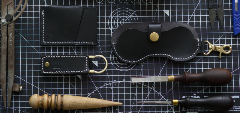 Holstein Collection of leather goods and tools on a grid-patterned surface