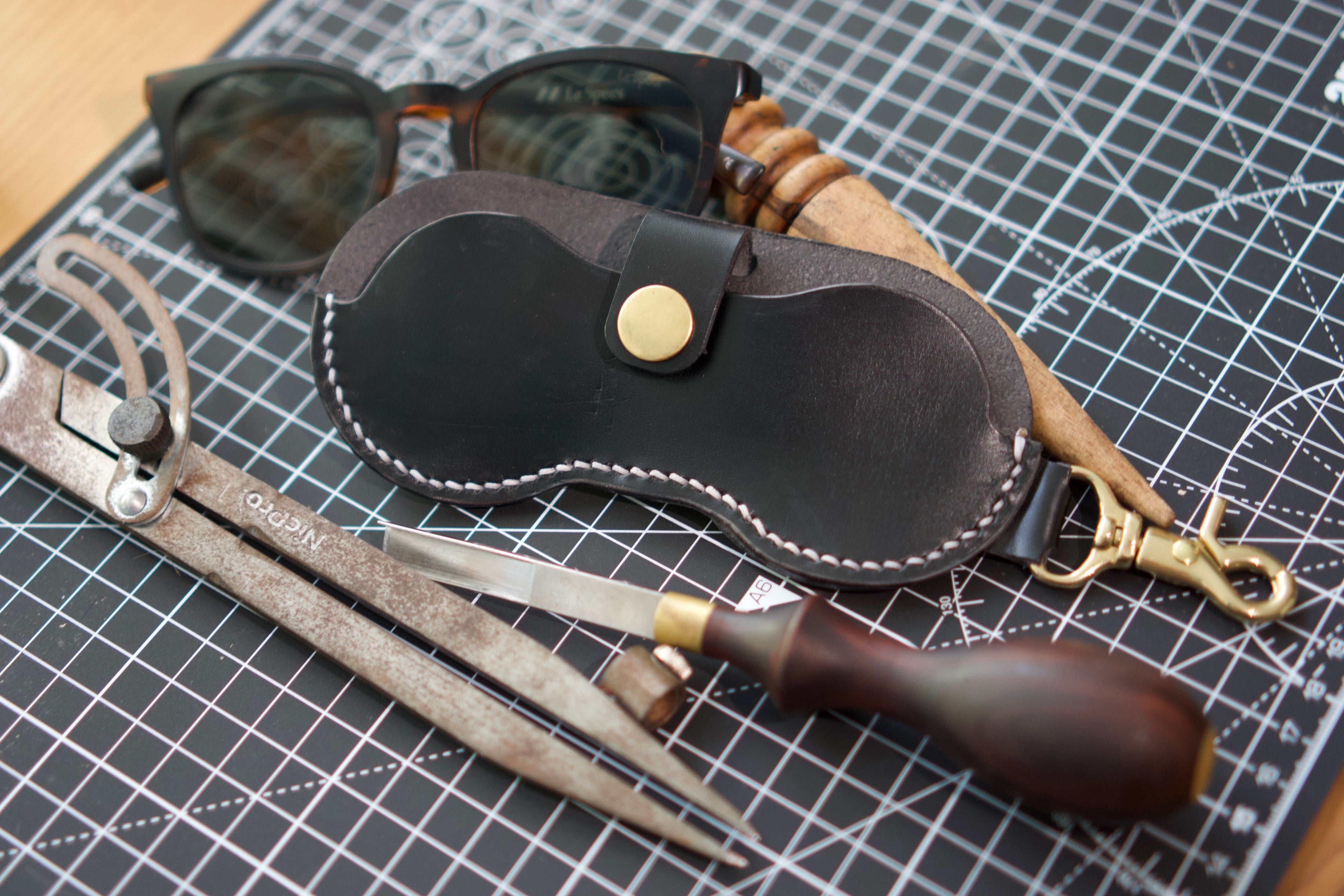Leather eyewear case with sunglasses on a grid surface