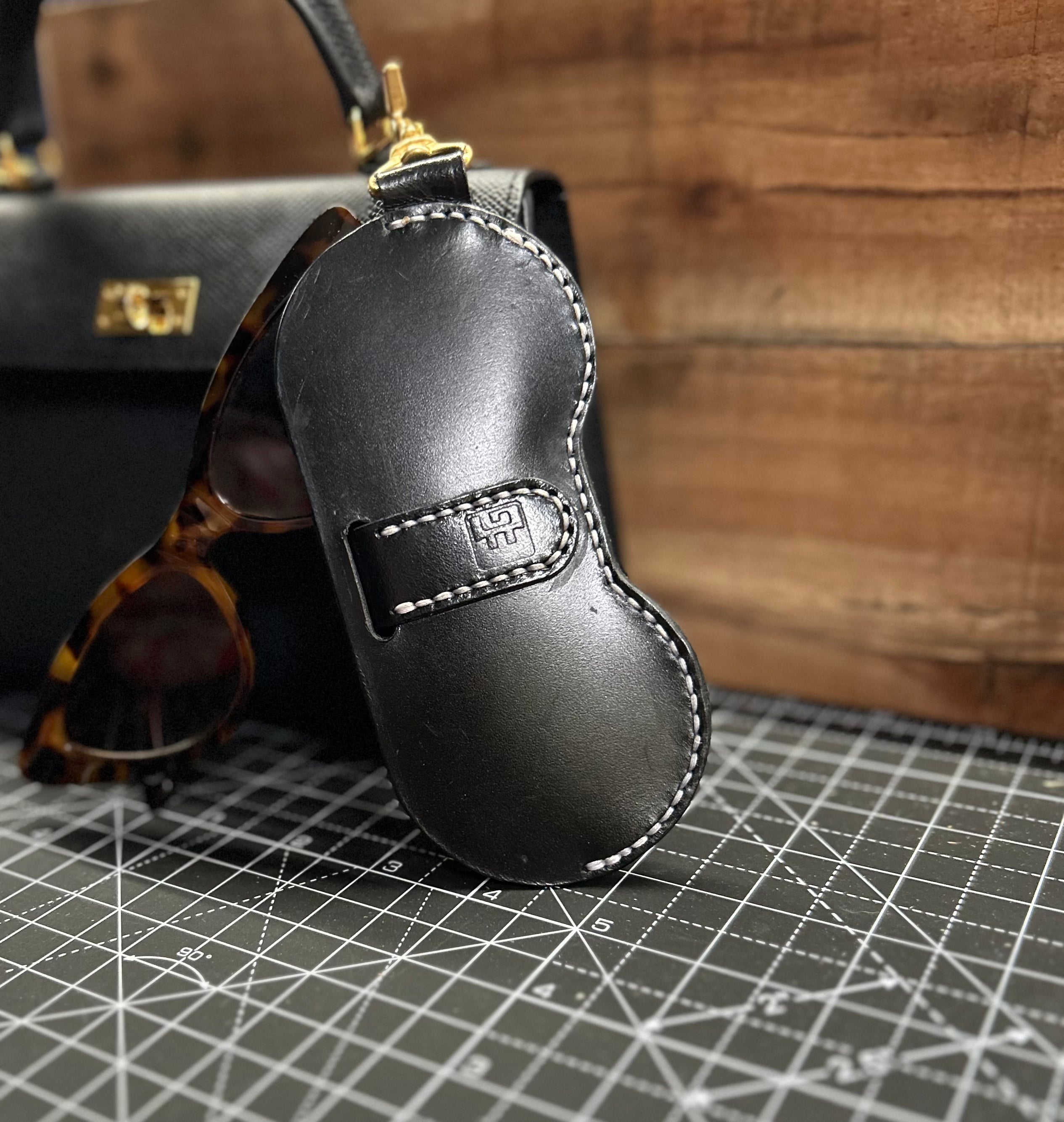 Black leather key case with sunglasses on a grid surface