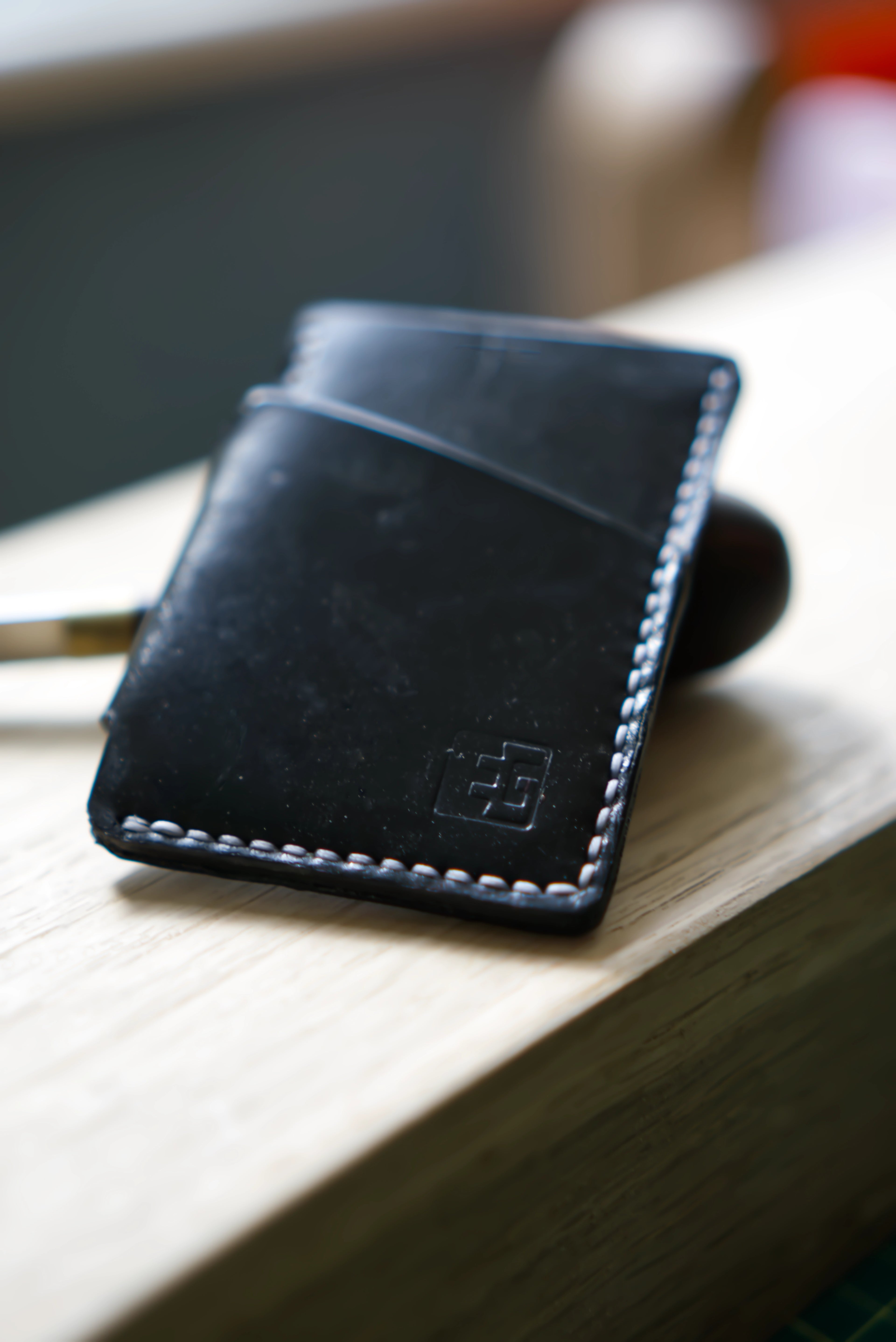 Black leather wallet on a wooden surface with a blurred background