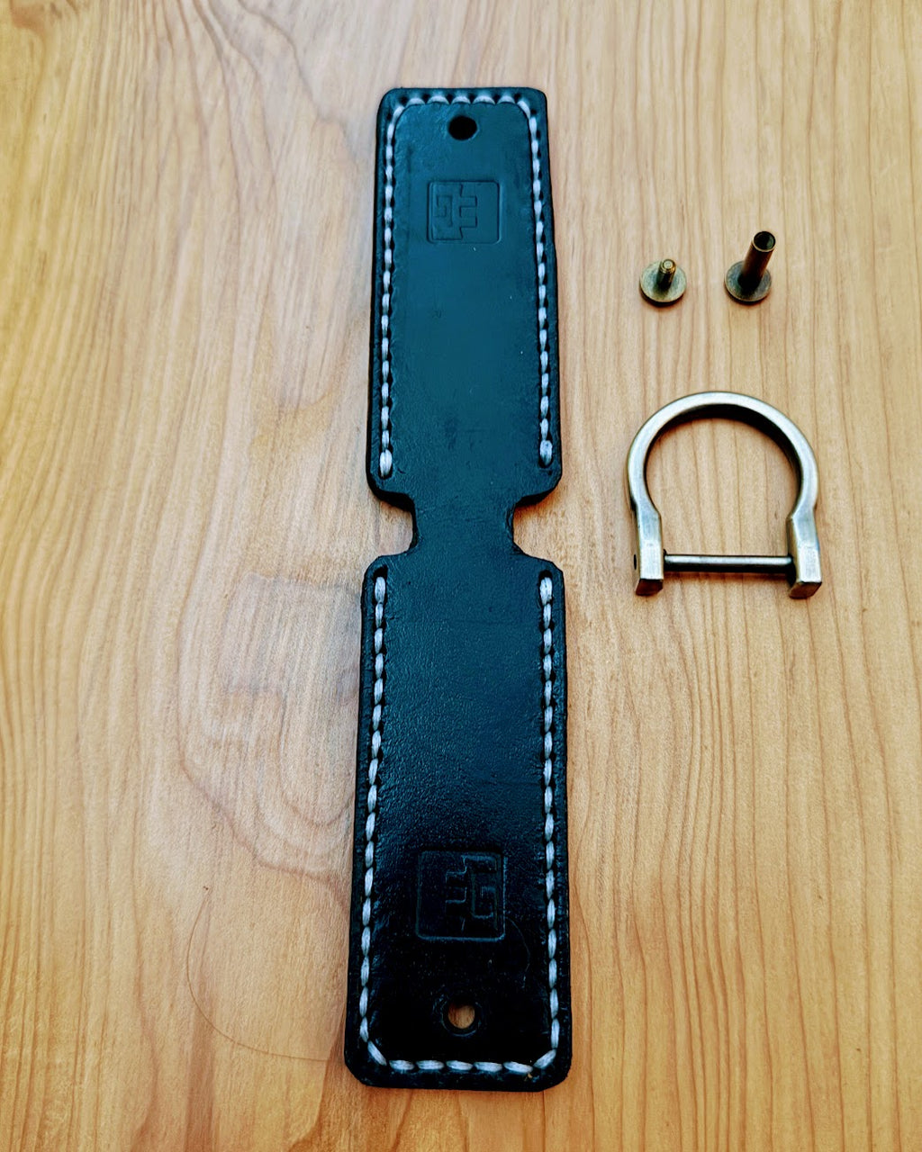 Black leather key fob with metal key ring on a wooden surface