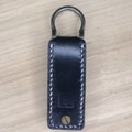Black leather key fob with metal keys on a wooden background