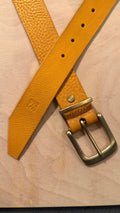Light tan pebble grain leather belt with a polished brass buckle, sunburst screw on the keeper and debossed Everbound mark on the angled tip