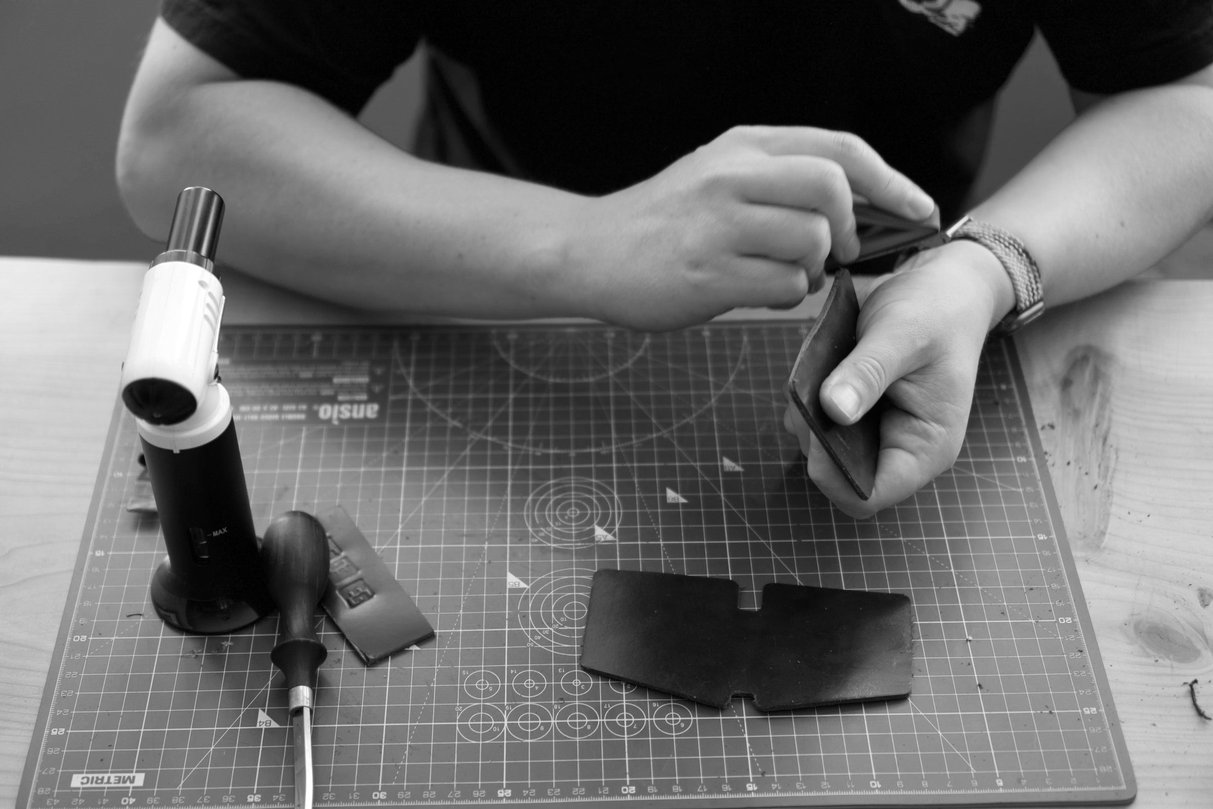 Person working on a leather project with tools on a cutting mat