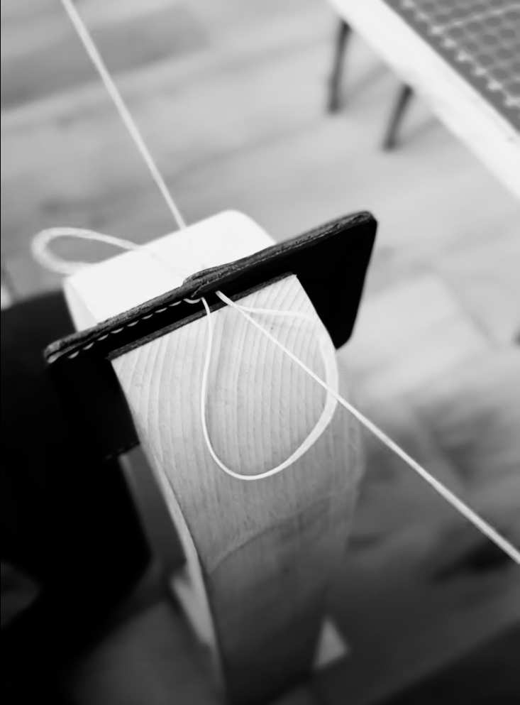 Wallet being hand stitched in white thread