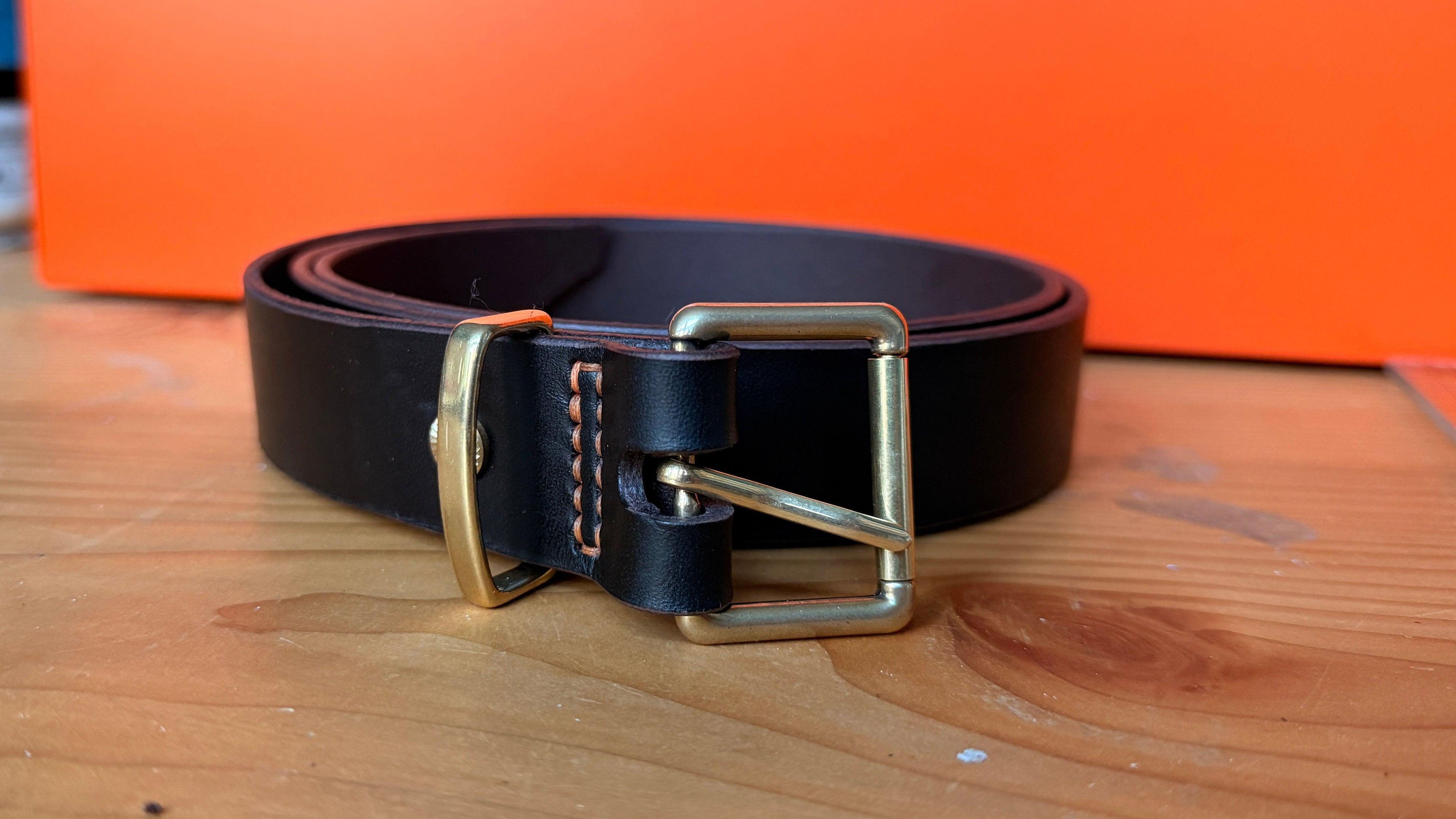 Brown leather belt with Brass buckle on a wooden surface